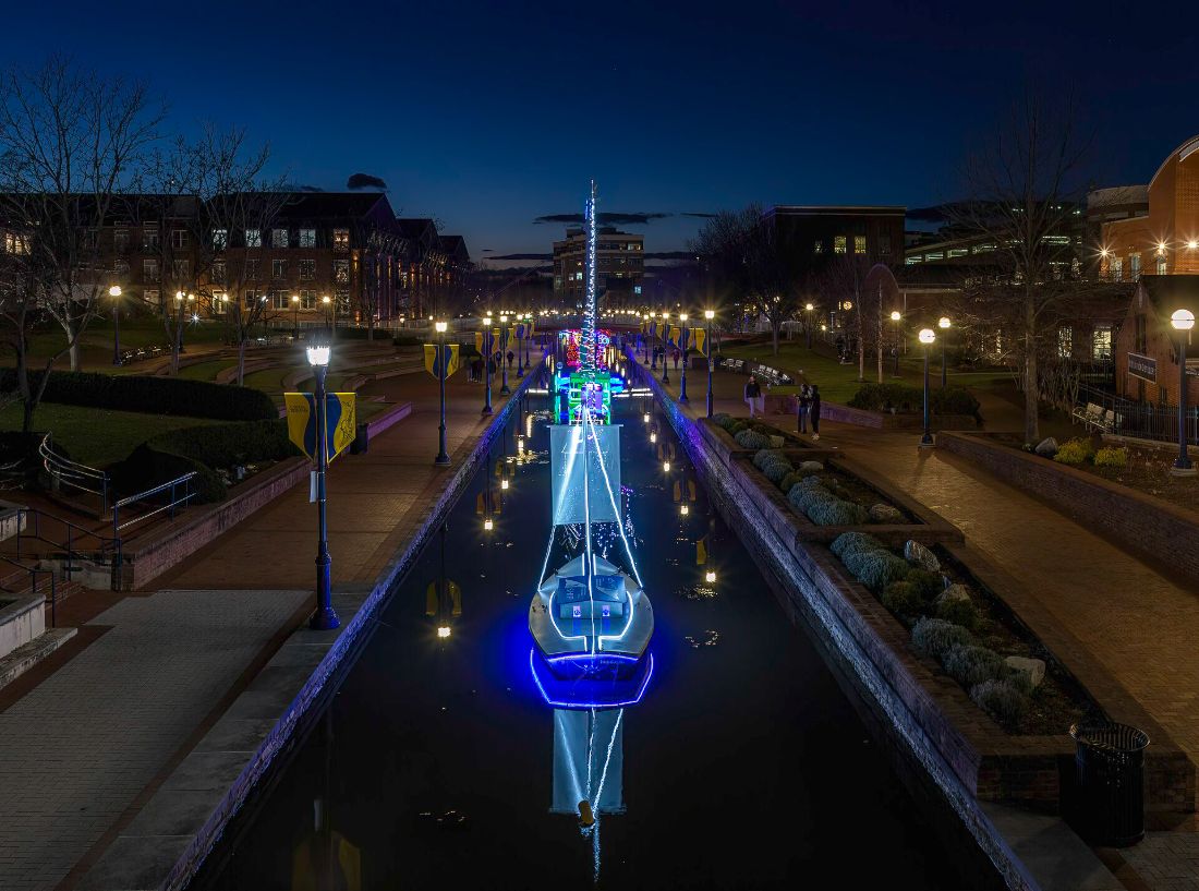 Illuminated sailboats moored along Carroll Creek in Frederick at dusk